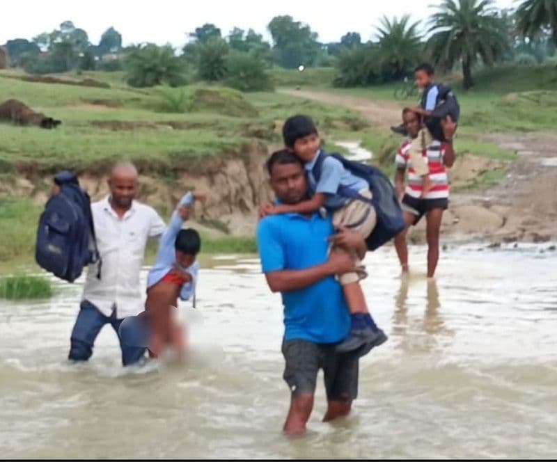 पुल नहीं होने से कंधों के सहारे स्कूली बच्चों को नदी पार करते हैं अभिभावक